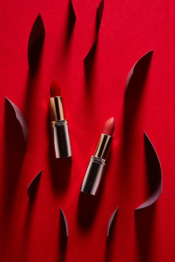 Dwie czerwone pomadki L'Oréal wśród czerwonych papierowych form