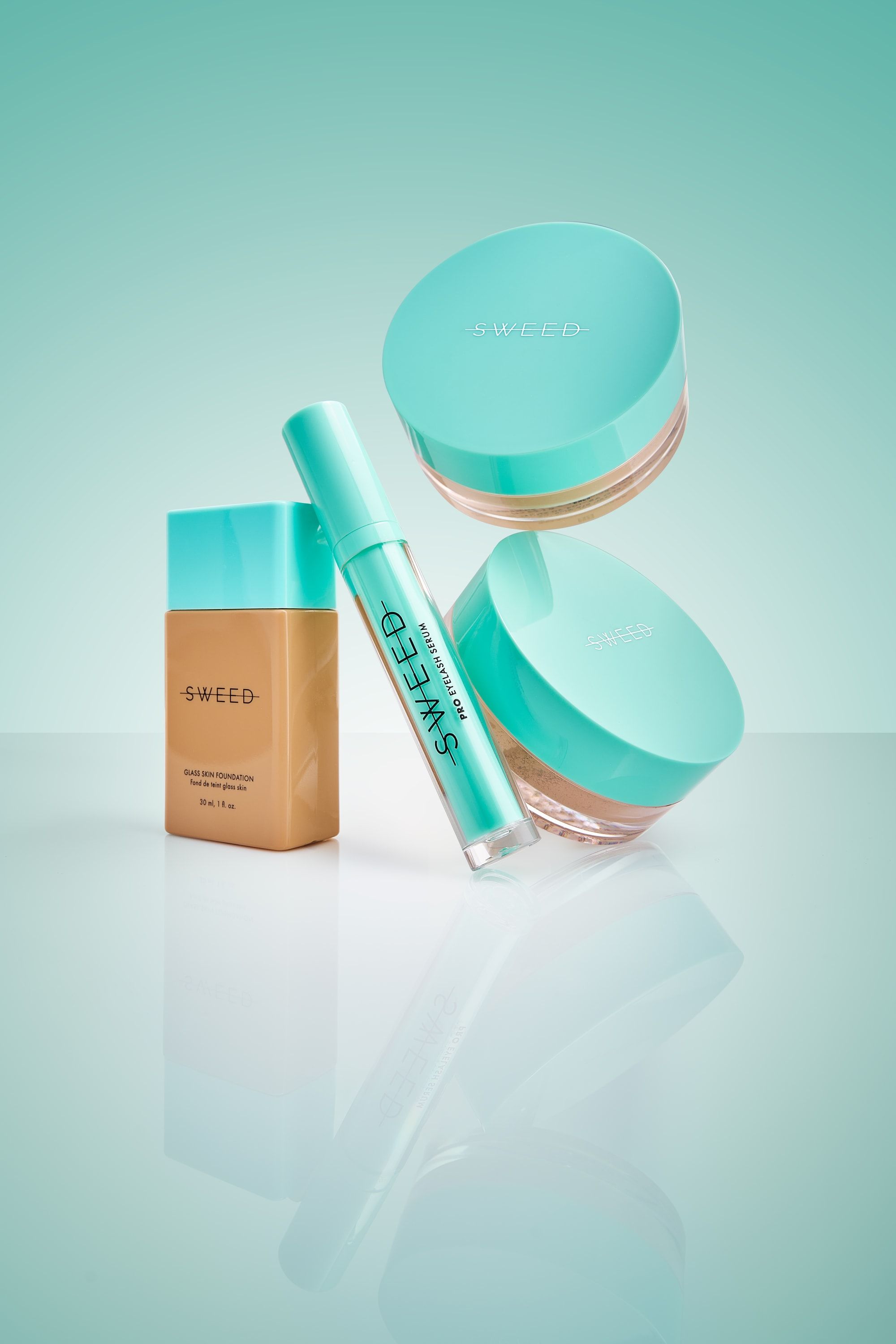 Podkład Glass Skin, serum do rzęs i dwa słoiczki pudru Sweed z miętowymi nakrętkami nad szklaną taflą