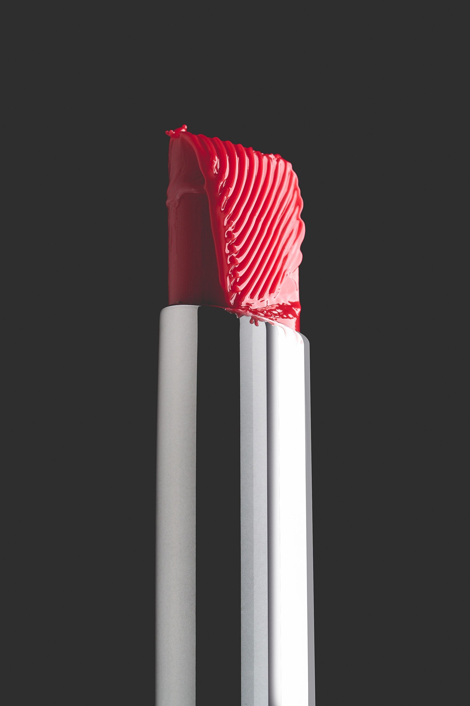Pomadka Buttery Lip Balm w odcieniu scarlet na grafitowym tle