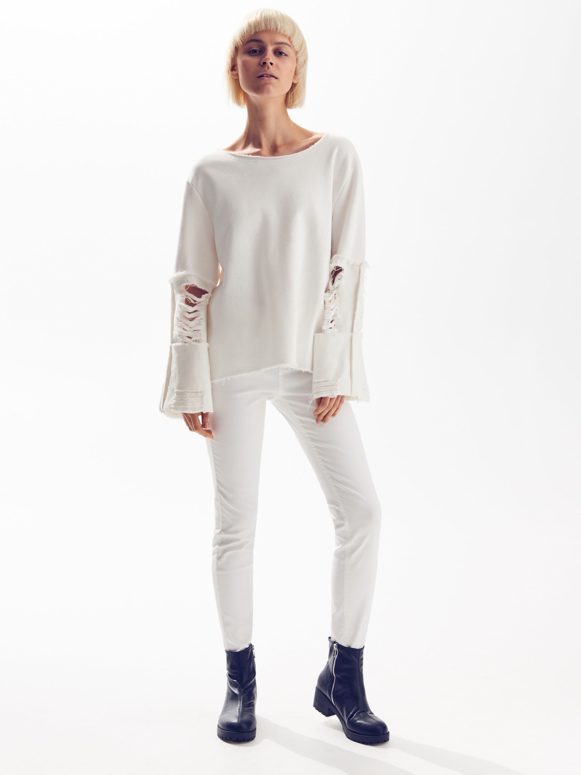 Modelka w białym swetrze i białych jeansach